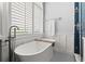 Bright bathroom featuring a soaking tub beneath a large window with wooden accents and tile flooring at 1060 Meadow Brook Dr, Woodstock, GA 30188