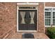Close-up of the front door with decorative curtains and brick exterior at 5101 Barrington Trace Dr, Atlanta, GA 30331