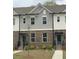 Well-maintained townhome featuring a brick facade, gray siding, and tidy front lawn at 1282 Ainsworth Aly, Sugar Hill, GA 30518