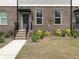 Close up of a brick townhome showing the front door, black awning, and small garden at 1282 Ainsworth Aly, Sugar Hill, GA 30518
