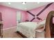 A pink bedroom featuring neutral carpet, accent wall, and window at 320 Creek Side Ct, Mcdonough, GA 30252