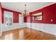Elegant dining room featuring red walls, decorative molding, chandelier, and hardwood floors at 4847 Sara Creek Way, Sugar Hill, GA 30518