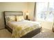 Bright bedroom featuring a large window, neutral walls, and a comfortable bed with yellow decorative pillows and throw blanket at 4125 Hidden River Dr, Cumming, GA 30028
