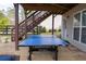 Patio area with ping pong table under raised deck with wooden steps to a backyard at 4125 Hidden River Dr, Cumming, GA 30028