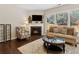 Cozy living room with fireplace, hardwood floors, and large windows overlooking the backyard at 6160 Shiloh Woods Dr, Cumming, GA 30040