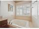 Soaking tub with tiled surround and a window with views of the yard at 1110 Croftmoore Lndg, Suwanee, GA 30024