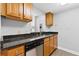 Galley kitchenette featuring wood cabinets, sleek black countertops, and stainless steel appliances at 1280 W Peachtree Nw St # 1712, Atlanta, GA 30309