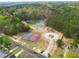 Community aerial view featuring a serene pond surrounded by lush trees, tennis and basketball courts, and the pool at 2061 Emerald Dr, Loganville, GA 30052