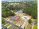 Community aerial view featuring a serene pond surrounded by lush trees, tennis and basketball courts, and the pool at 2061 Emerald Dr, Loganville, GA 30052