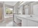 Bathroom featuring dual sinks, a soaking tub, and a large window with wooded view at 2061 Emerald Dr, Loganville, GA 30052