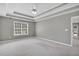 Large primary bedroom with a tray ceiling, neutral colors, and abundant natural light from a large window at 2061 Emerald Dr, Loganville, GA 30052
