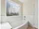 Bathroom featuring tub with decorative window and white tile walls at 7902 West Shore Cir, Riverdale, GA 30296