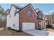 Side view of a brick home with a two-car garage and white siding on the second story at 7902 West Shore Cir, Riverdale, GA 30296