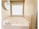 Relaxing soaking tub with tile surround and chrome fixtures situated near a window at 2050 Harvest Ridge Cir, Buford, GA 30519