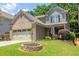 Well-manicured lawn surrounds this home with a brick and shingle facade and a two-car garage at 2050 Harvest Ridge Cir, Buford, GA 30519