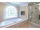 Luxurious bathroom featuring a soaking tub, separate glass shower, and a large arched window at 1864 Crestridge Ne Pl, Atlanta, GA 30345