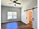 Large bedroom with dark laminate floors and a barn door leading to the bathroom at 2152 Castlewood St, East Point, GA 30344