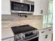 Modern kitchen featuring stainless steel appliances, stone backsplash, and white cabinets with dark hardware at 2152 Castlewood St, East Point, GA 30344
