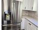 Kitchen featuring a stainless steel refrigerator, white cabinets, and modern stone backsplash at 2152 Castlewood St, East Point, GA 30344