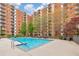 Outdoor pool surrounded by chairs and trees in front of a brick apartment building on a partly cloudy day at 300 Johnson Ferry Ne Rd # A1008, Atlanta, GA 30328