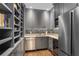 A butler's pantry with gray cabinets, open shelving, stainless steel appliances, and a tiled backsplash at 219 Little John Ne Trl, Atlanta, GA 30309
