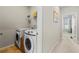 Compact laundry room including a washer and dryer with storage shelf and a hallway view at 6023 Skellig St, Norcross, GA 30071