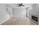Bright living room featuring hardwood floors, a ceiling fan, fireplace, and staircase at 7040 Magnolia Park Ln, Norcross, GA 30093