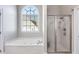 Bathroom featuring a bathtub beneath an arched window and glass shower at 2006 Hubbard Ct, Villa Rica, GA 30180
