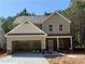 Two-story home features a two-car garage and a covered entryway with stone accents at 48 Beaver Pt, Villa Rica, GA 30180