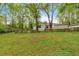 Exterior view of a spacious grassy backyard surrounded by trees and a rustic fence at 1965 Midway Rd, Douglasville, GA 30135