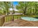 Backyard view of an above ground pool surrounded by a wood deck and lush green trees at 1965 Midway Rd, Douglasville, GA 30135
