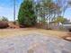 Stone-paver patio in fenced backyard is surrounded by mature trees and grass at 2112 Little River Dr, Suwanee, GA 30024