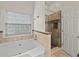 Bright bathroom with a garden tub and glass-enclosed shower, complete with tiled surround at 2112 Little River Dr, Suwanee, GA 30024