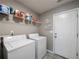Well-lit laundry room with a gray tile floor includes white washer and dryer units and storage shelves at 2112 Little River Dr, Suwanee, GA 30024