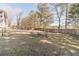 View of the backyard with mature trees, and patio with a firepit at 241 Rockingham Dr, Loganville, GA 30052