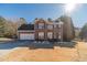 Charming two-story brick home with attached two-car garage, green lawn, and bright blue sky at 241 Rockingham Dr, Loganville, GA 30052