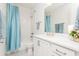 A well-lit bathroom with white cabinets, a white countertop, and a shower with a blue curtain at 437 Great Pine Way, Woodstock, GA 30188