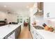 Open-concept kitchen boasts white cabinets, stainless steel hood, gas range, island with sink at 437 Great Pine Way, Woodstock, GA 30188