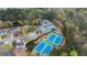An aerial view of a community clubhouse, tennis courts, and pool amidst lush greenery at 226 Double Gate Ct, Sugar Hill, GA 30518