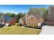 Traditional brick home with well-manicured lawn, mature trees, and three-car garage at 226 Double Gate Ct, Sugar Hill, GA 30518