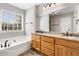 Bright bathroom featuring double sinks with granite countertops, tub, and a large window at 3227 Grove Trl, Acworth, GA 30101