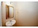 A small powder room featuring a pedestal sink, a framed mirror, and a decorative light fixture at 5364 Hickory Knl, Norcross, GA 30071