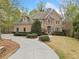 Stately stucco home featuring an arched entry, stone accents, and a circular driveway, surrounded by lush landscaping at 940 Magnolia Blossom Ct, Alpharetta, GA 30005