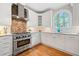 Stylish kitchen features a professional range, custom backsplash, stone countertops, and shaker cabinets at 940 Magnolia Blossom Ct, Alpharetta, GA 30005