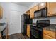 Efficient kitchen with granite counters, wood cabinets, black appliances, and hardwood flooring at 4333 Dunwoody Park # 1211, Atlanta, GA 30338
