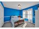 Bright bedroom with blue walls, white trim, a cozy bed, and a window with natural light, creating a peaceful retreat at 735 Ambur Cove Way Nw, Lawrenceville, GA 30043