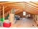 Unfinished attic space with exposed wood beams, storage, and natural light from a window at 103 New Hood Rd, Stockbridge, GA 30281