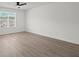 An empty bedroom is brightened by a large window and has modern hardwood floors at 209 Emma Gilley Dr, Carrollton, GA 30116