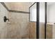 Shower with travertine style tile, decorative tile accent, and black framed glass door at 5925 Pine Bluff Dr, Cumming, GA 30040