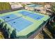 Aerial view of community tennis courts with blue surface, surrounded by dark fences and green landscape at 5925 Pine Bluff Dr, Cumming, GA 30040